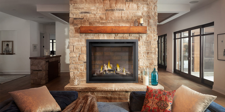 A rustic-inspired living room with a large brick hearth and a square, traditional looking gas fireplace