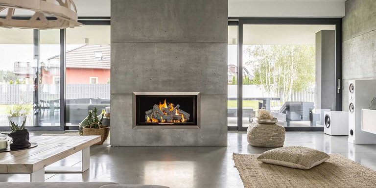 A large contemporary living room with a natural stone partition in the center and a rectangular gas fireplace with a rustic gas log set