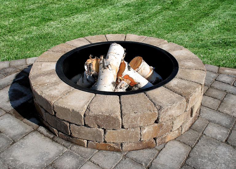 A Necessories steel fire pit ring installed in a DIY masonry stone wood burning fire pit