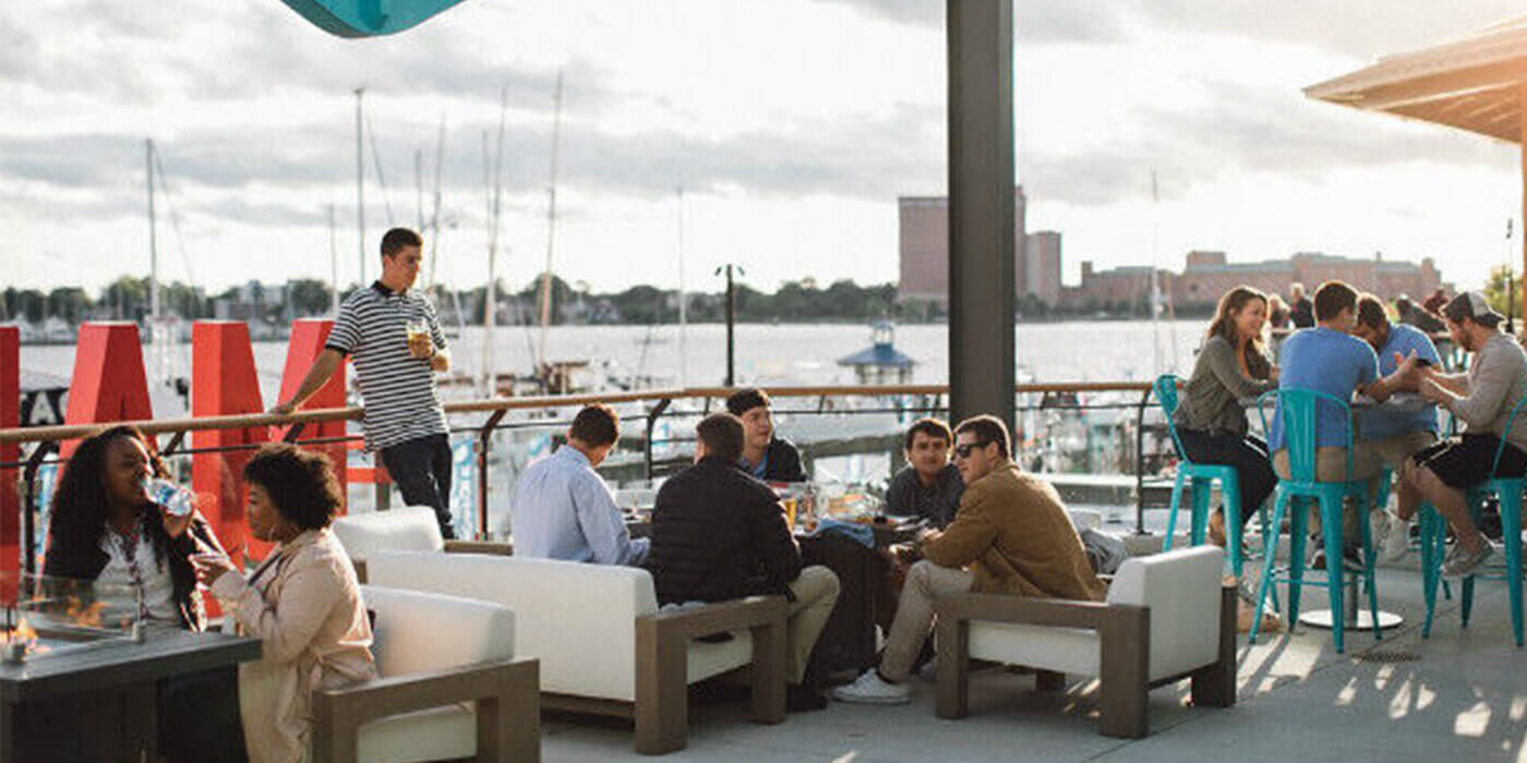 People drinking and dining on an outdoor patio next to the ocean