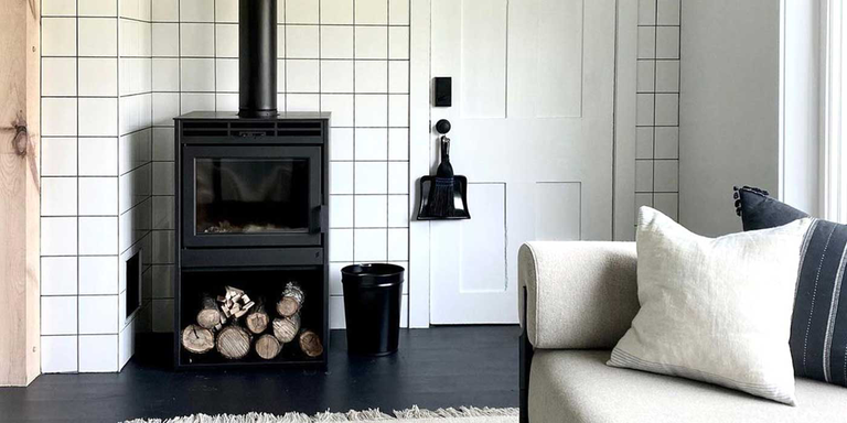 A black wood burning stove with a log storage area built in underneath the firebox