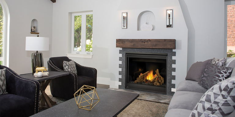 A modern indoor living space with a traditional square gas fireplace with a custom surround and a dark wood mantel