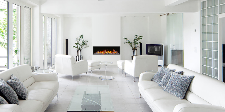 A minimalist living space with all white furniture and walls and a medium sized linear electric fireplace