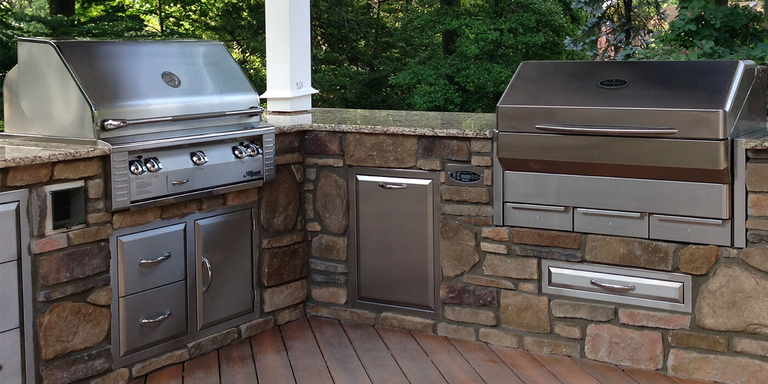 A L-shaped outdoor kitchen with two stainless steel grills
