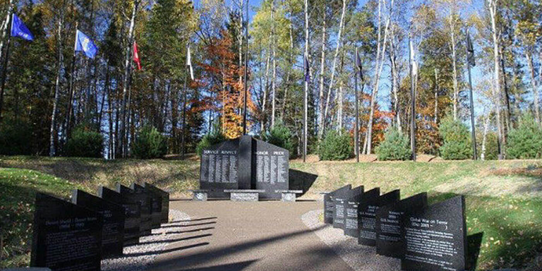 Pathway to gray granite veteran memorial in the woods
