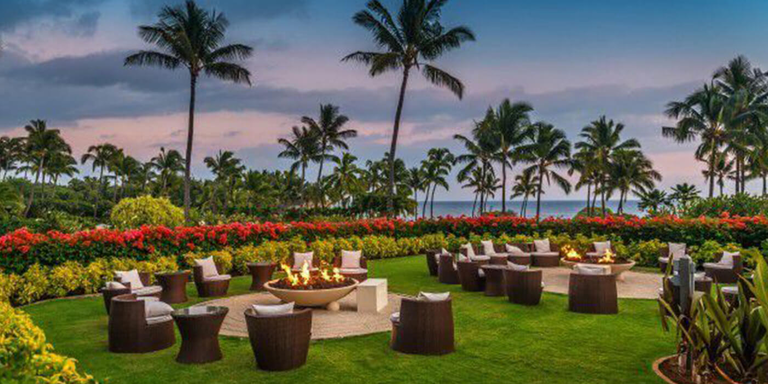Gas fire pits surrounded by chairs at a Hawaiian resort during sunset