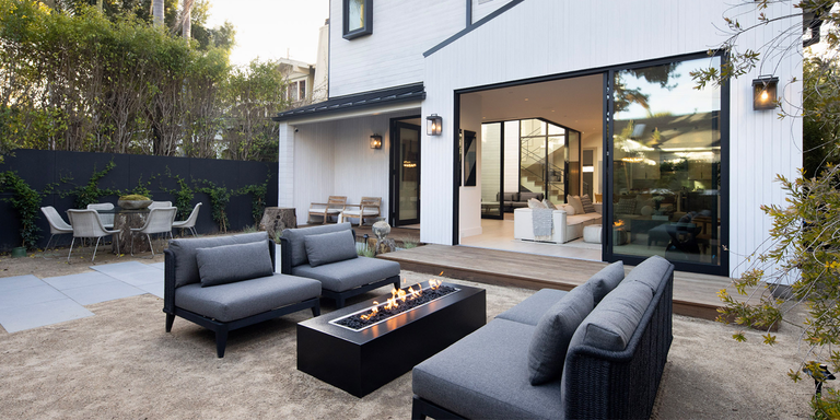 A modern outdoor space with a lounging area and linear gas fire pit 