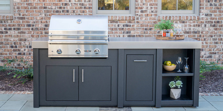 A small outdoor kitchen island with a stainless steel grill head, a refrigerator, and built-in storage doors and drawers.