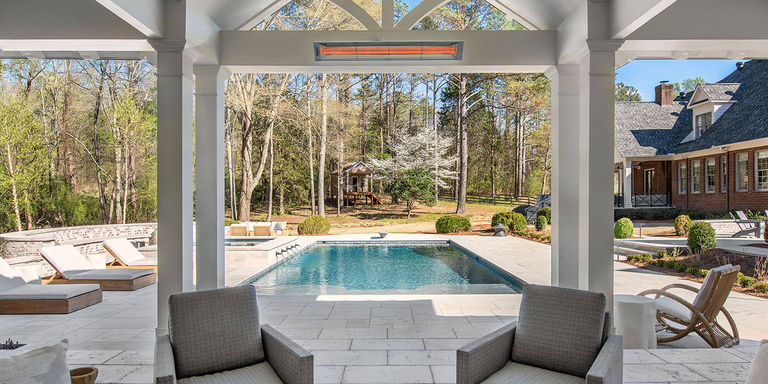 An partially enclosed outdoor patio space with a pool, sitting area, and a wall mounted Infratech patio heater