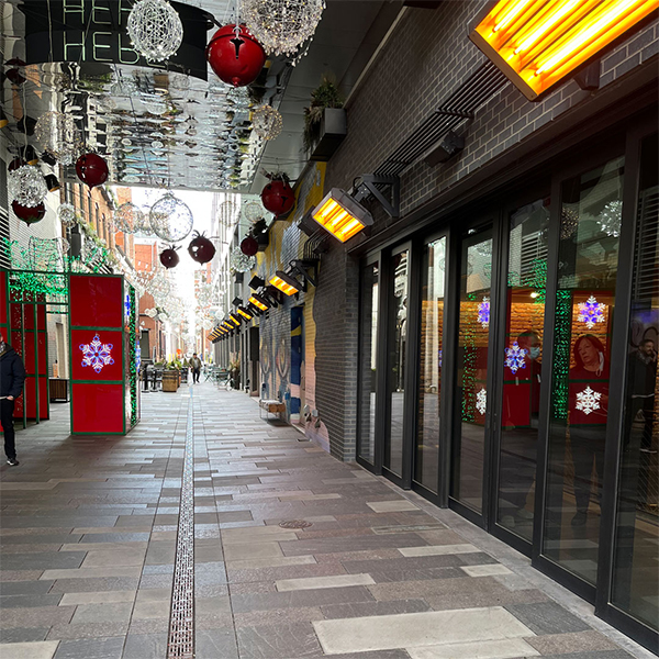 An outdoor shopping center with several Detroit Radiant ELX Series electric outdoor heaters mounted to the awnings outside the store doors